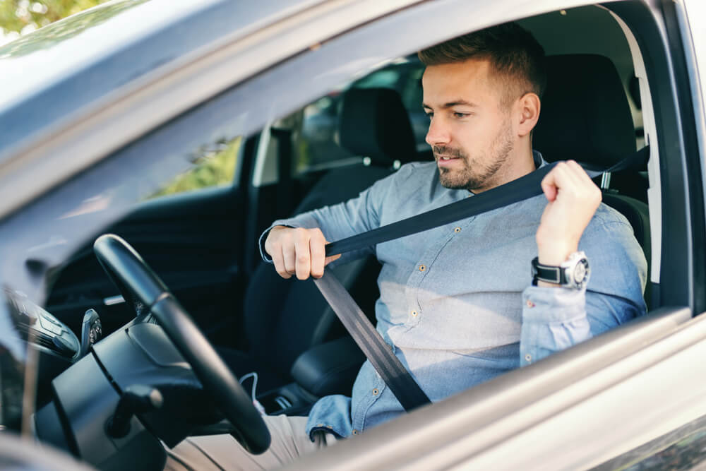 Driver fastening his seatbelt for safety.