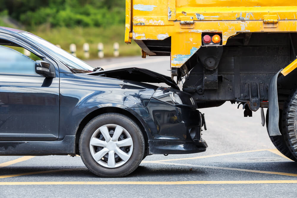 Accident on the road involving black car tail gaiting the yellow truck.