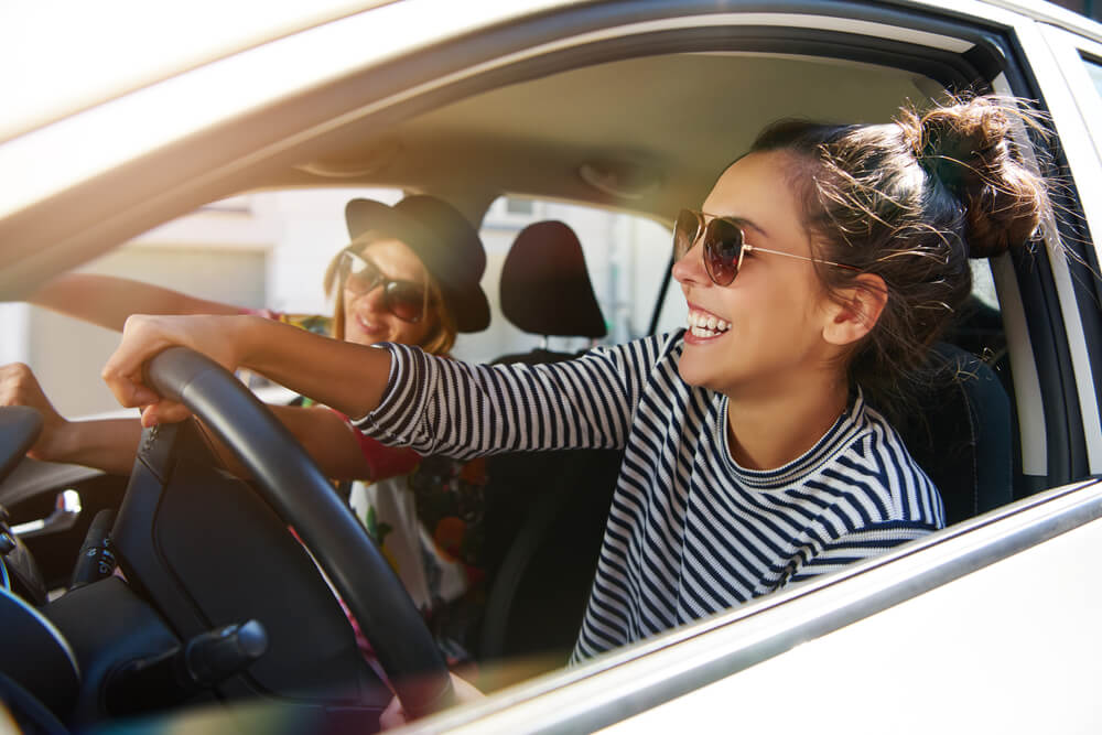Young lady driver happily driving her car.
