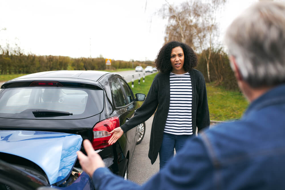Angry lady driver pointing the damage from car accident.