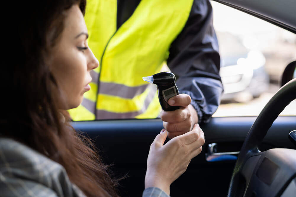 Drunk lady driver taking breathalyzer test.