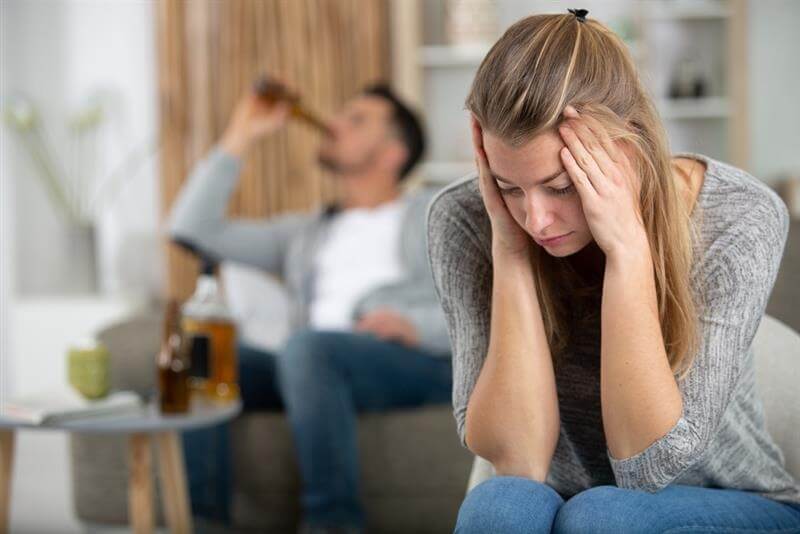 Sad lady holding hands on head thinking of divorce for habitual drunkenness of husband.