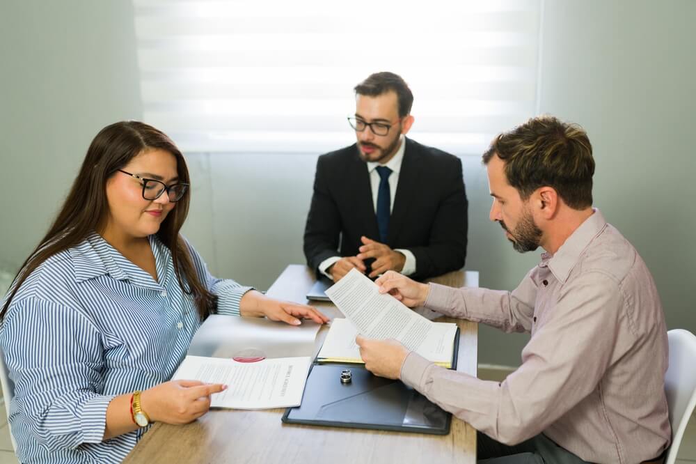 Serious couple having a meeting with an attorney, discussing and signing legal documents for a separation or divorce agreement.